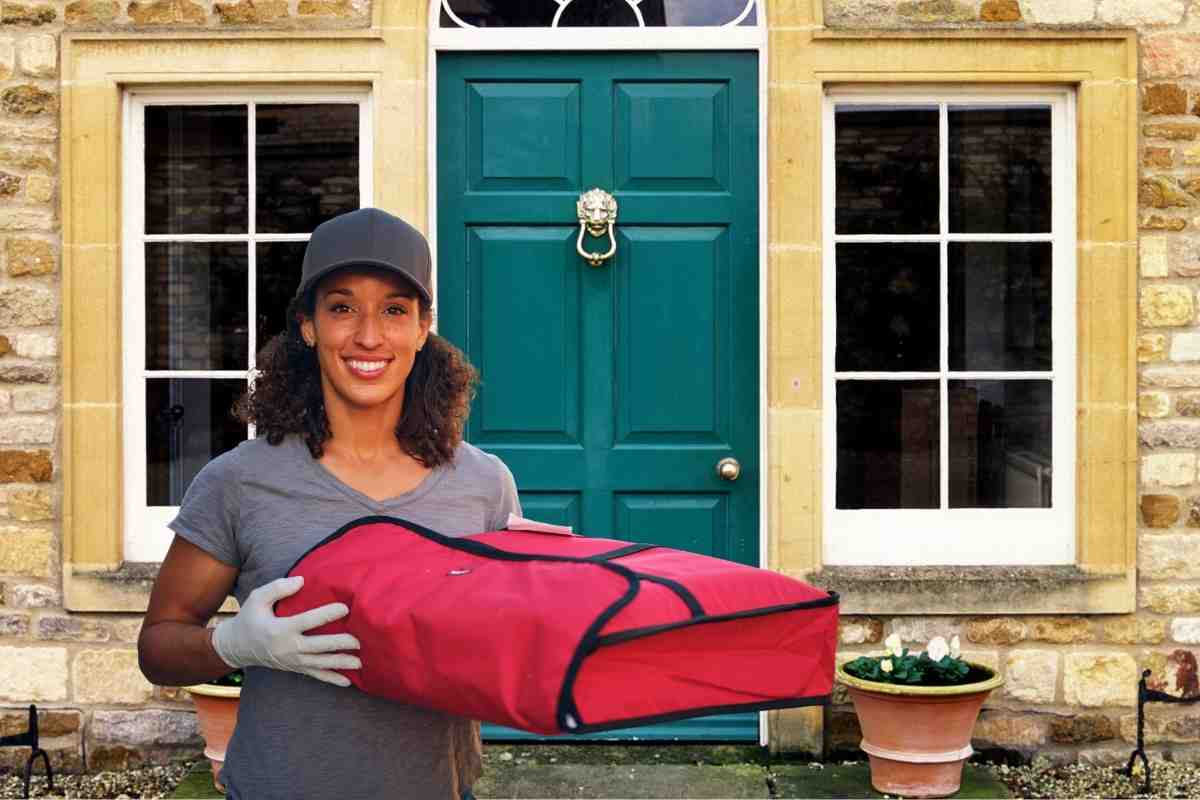 Woman holding pizza bag outside her house